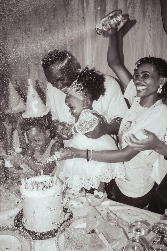Happy family celebrating a birthday with cake and confetti indoors. Laughter and joy fill the atmosphere.